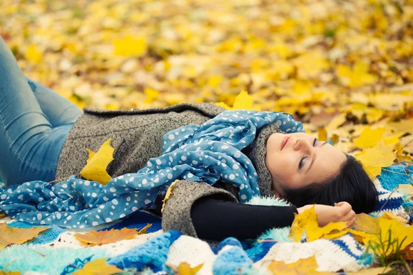 Junge Frau legt sich in Herbstlaub — Stockfoto