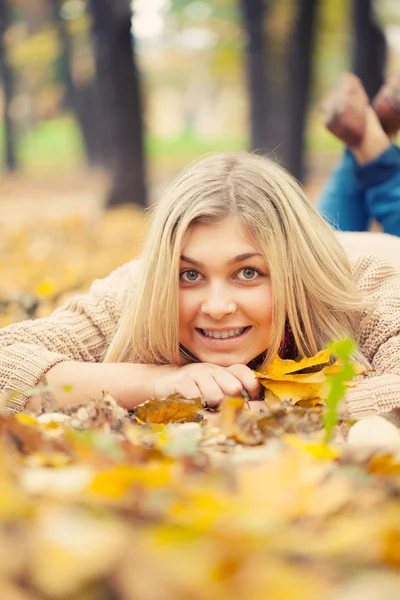 Mladá žena, kterým se stanoví na zemi v podzimním parku — Stock fotografie