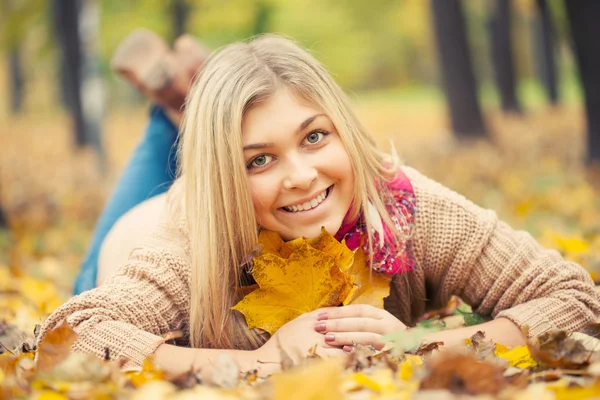 Giovane donna sdraiata a terra nel parco autunnale — Foto Stock