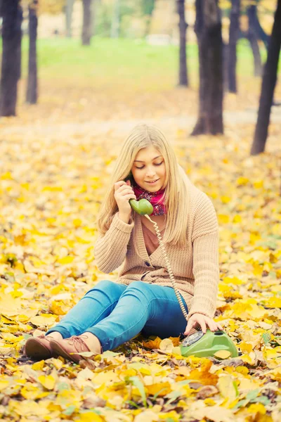 Young woman talking on vintage phone in autumn park — Stock Photo, Image