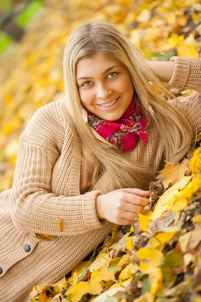 Young woman laying down on the ground in autumn park — Stock Photo, Image