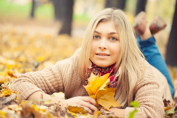 Junge Frau legt sich im Herbstpark auf den Boden — Stockfoto