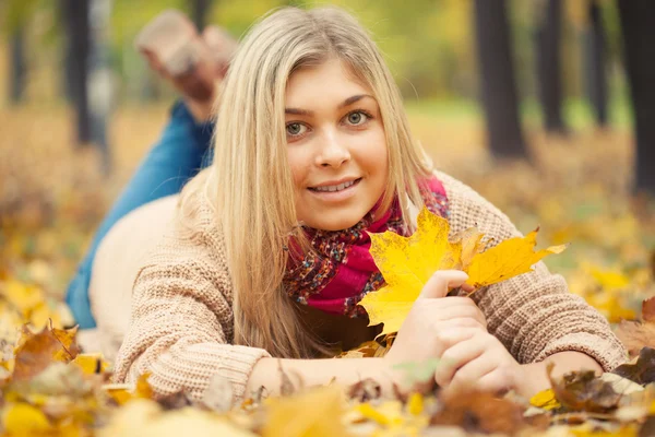 Giovane donna sdraiata a terra nel parco autunnale — Foto Stock