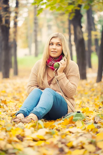 Young woman talking on vintage phone in autumn park — Stock Photo, Image
