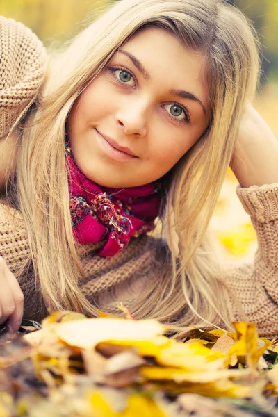 Junge Frau legt sich im Herbstpark auf den Boden — Stockfoto