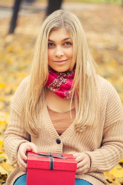 Young woman with present in autum park — Stock Photo, Image