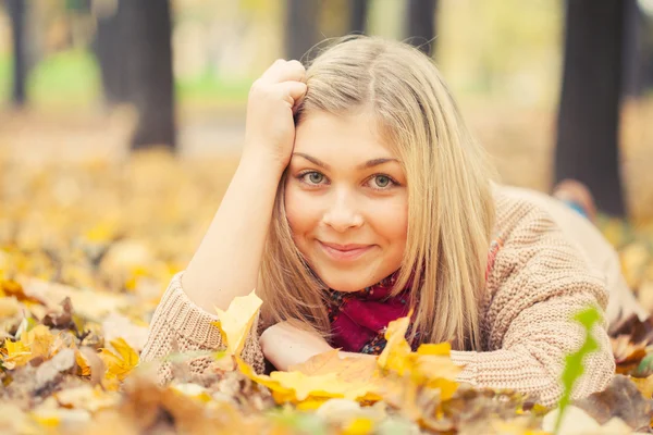 Ung kvinna fastställande på marken i höst park — Stockfoto