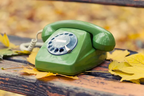 Grünes Oldtimer-Handy auf Bank im Herbstpark — Stockfoto