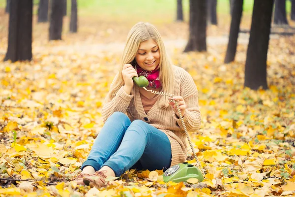 Young woman talking on vintage phone in autumn park — Stock Photo, Image