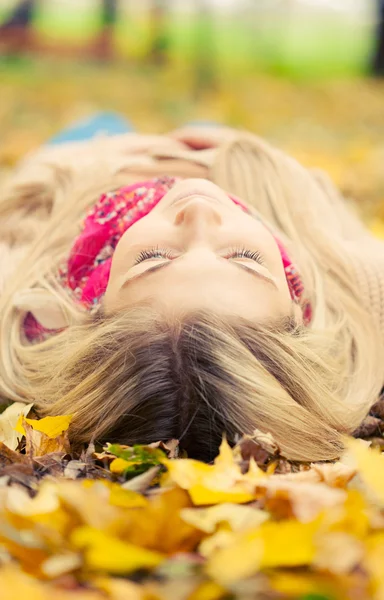 Junge Frau legt sich im Herbstpark auf den Boden — Stockfoto