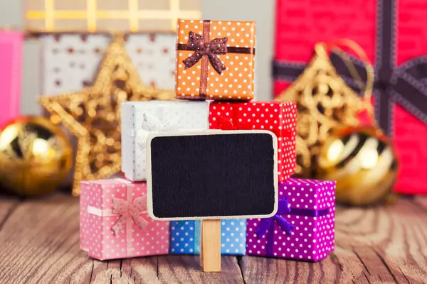 Small blackboard against gift boxes — Stock Photo, Image