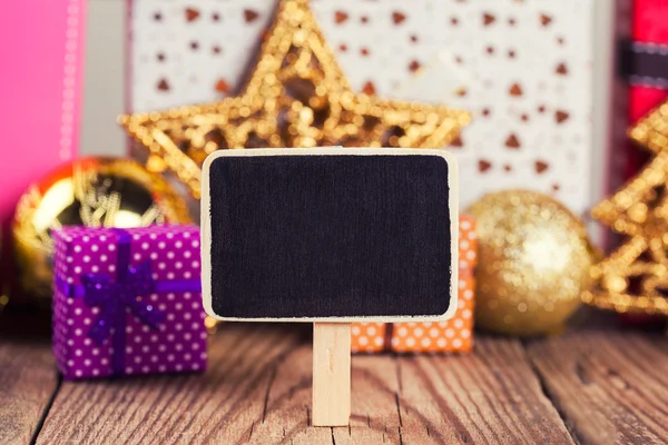Small blackboard against gift boxes — Stock Photo, Image