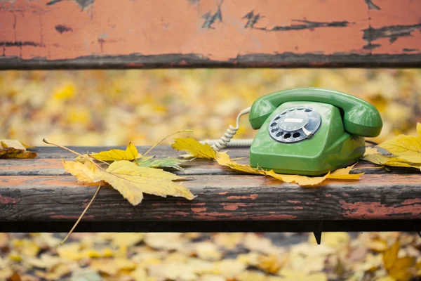 Grünes Oldtimer-Handy auf Bank im Herbstpark — Stockfoto