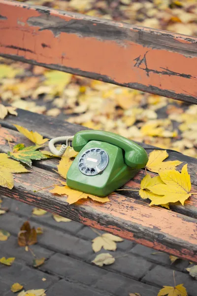 Grünes Oldtimer-Handy auf Bank im Herbstpark — Stockfoto