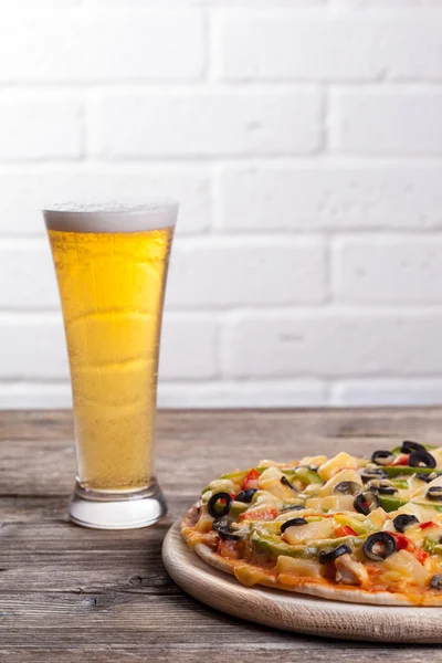 Пицца на столе со стаканом пива — стоковое фото