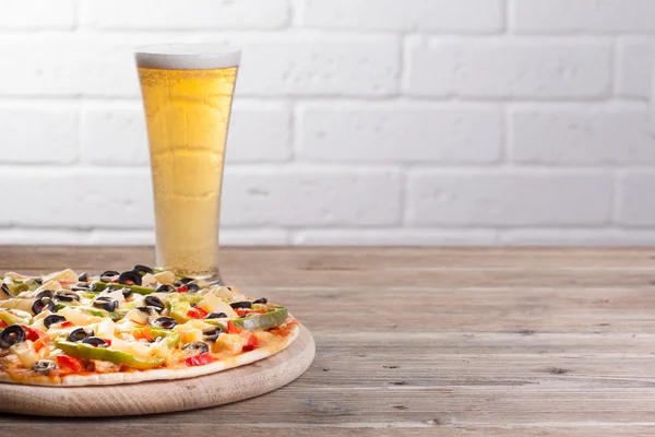 Пицца на столе со стаканом пива — стоковое фото