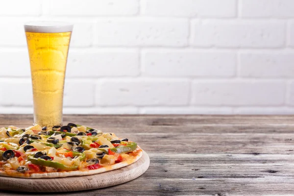 Pizza op de tafel met een glas bier — Stockfoto