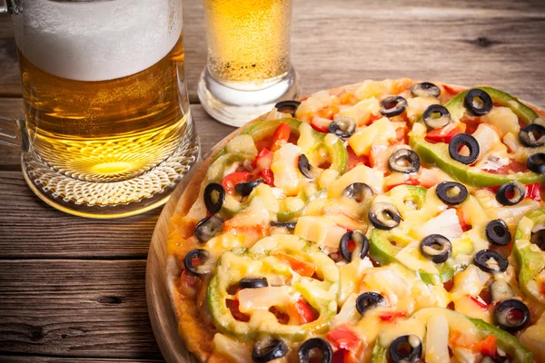 Pizza en la mesa con un vaso de cerveza — Foto de Stock