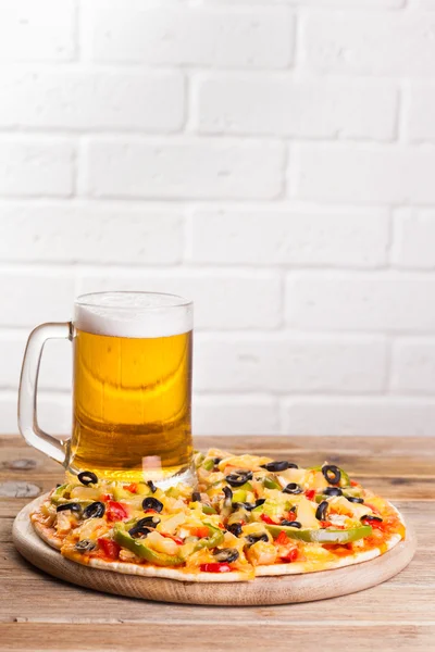 Pizza en la mesa con un vaso de cerveza — Foto de Stock