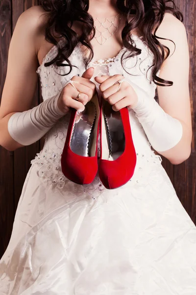 Novia sosteniendo un par de zapatos rojos — Foto de Stock