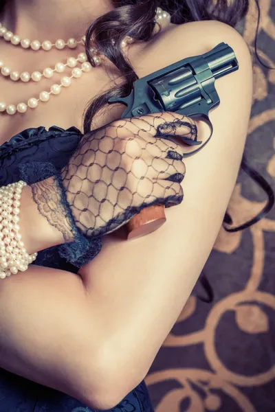 Frau trägt schwarzes Korsett und Perlen und hält eine Waffe in der Hand — Stockfoto