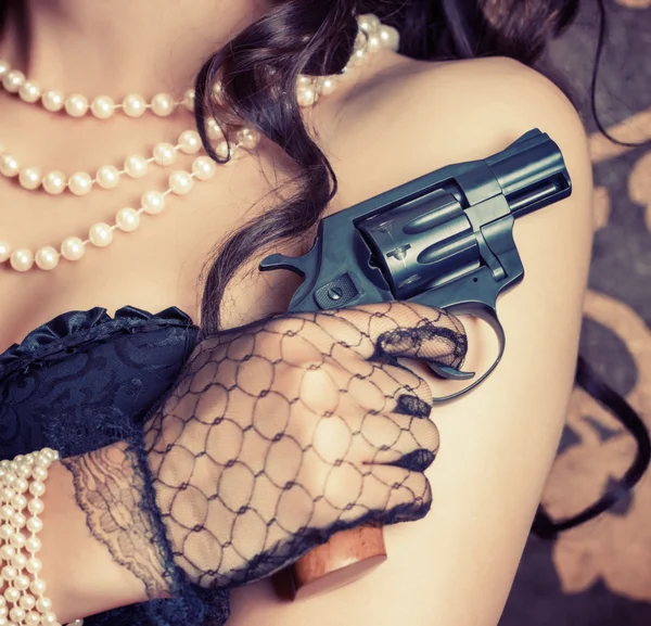 Mujer vistiendo corsé negro y perlas y sosteniendo un arma — Foto de Stock