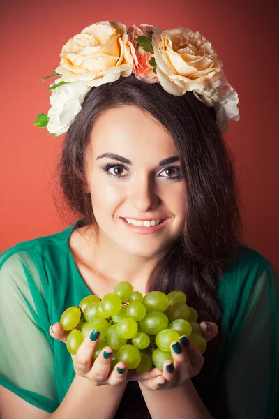 女性の身に着けている花輪と緑色のブドウを保持 — ストック写真
