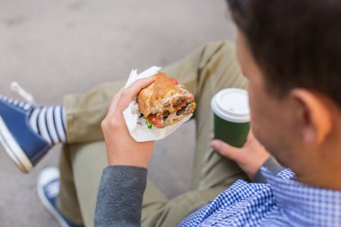 Gülümseyen adam yemek yiyor bankta