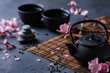 Çaydanlık ve çay fincanları ve çiçek açan badem ağacı dalları.