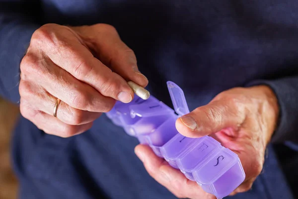 Senior retired man taking medicine , pills. Closeup of hands