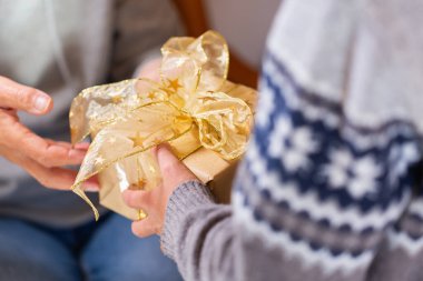 Closeup of hands of senior woman and a child holding a gift at Christmas