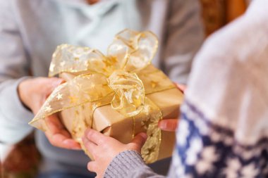 Closeup of hands of senior woman and a child holding a gift at Christmas