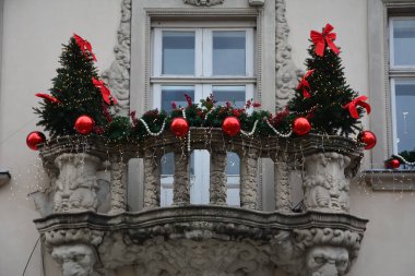 Noel ağacı sınırlı, renkli Noel topları ve açık çelenklerle balkonun Noel süslemesi. Yılbaşı arifesinde binaların dekorasyonu ve sokak aydınlatması.