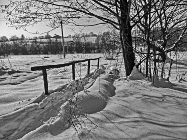 Güneşin doğuşunda ve batışında karda yol. Ormandaki karda ayak izleri. Kış dönemi. İzler, taze karda insan izleri. Kar yağışı. Siyah ve beyaz resim.