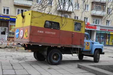 Rivne. Ukraine. November, 2021.municipal blue red yellow color ussr old electric service and water supply repair GAZ 53, vintage classic car arriving on emergency call drive on city urban street