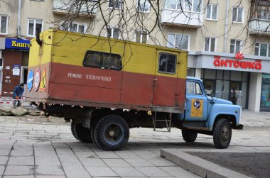 Rivne. Ukraine. November, 2021.municipal blue red yellow color ussr old electric service and water supply repair GAZ 53, vintage classic car arriving on emergency call drive on city urban street