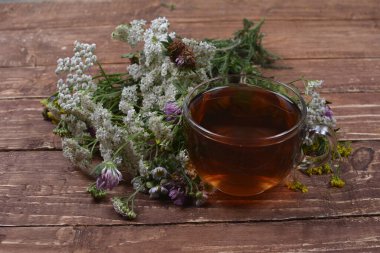 Çeşitli kurutulmuş çayır otları ve hafif eski ahşap masa üzerinde bitki çayı. Fizyoterapi ve sağlık promosyonu için tıbbi bitkiler hazırlanıyor.