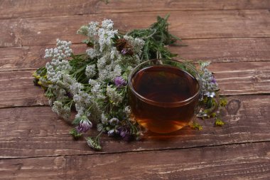 Çeşitli kurutulmuş çayır otları ve hafif eski ahşap masa üzerinde bitki çayı. Fizyoterapi ve sağlık promosyonu için tıbbi bitkiler hazırlanıyor.
