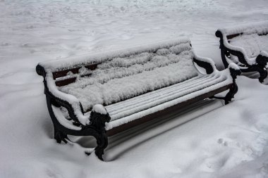 Kışın karla kaplı park bankında. Karlı soğuk hava. Kar yağdıktan sonra kış sabahı. Açık hava bankı karla kaplı.