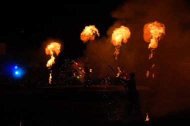 Lviv. Ukrayna. Ağustos 2021. Efsanevi bir yaratığın maskesi içindeki bir ateş sanatçısı ateşle gösteri yapıyor. Sokak kültürü festivali. Gecenin renkli mistik yangın gösterisi. Ateşli bir gece performansının bulanık görüntüsü..