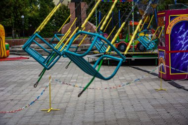 Atlıkarınca çocuk koltukları lunaparkta hızla koşuyor. Boş çocukların atlıkarıncaları kanatlarda bekliyor.