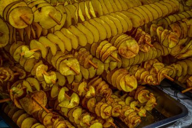 Patates sarmalı ya da kasırga, şiş şişte kızartılmış ve düşük derinlikte ateş edilmiş. Patates kızartması, ahşap çubuklar, spiral. Sağlıksız kızarmış yemek. Sokak yemeği, çubukta kızarmış patates.
