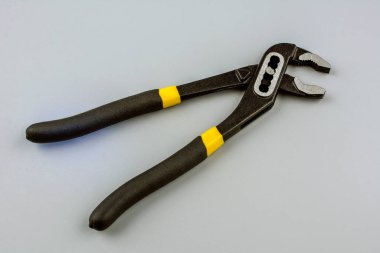 Açık çeneli ve sarı plastik saplı metal el işi bir alet. Tutmak, kavramak ve döndürmek ya da sıkmak ve sıkmak için.