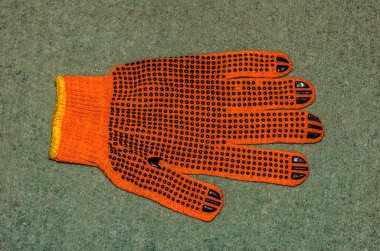 Turuncu iş eldivenleri bahçedeki ahşap bir tahtanın üzerinde yatıyor. .