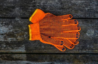 Turuncu iş eldivenleri bahçedeki ahşap bir tahtanın üzerinde yatıyor. .