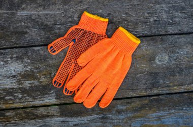 Turuncu iş eldivenleri bahçedeki ahşap bir tahtanın üzerinde yatıyor. .