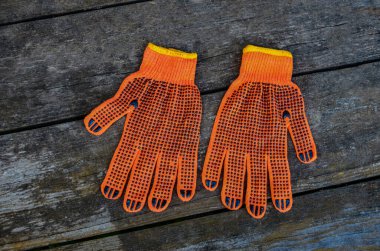 Turuncu iş eldivenleri bahçedeki ahşap bir tahtanın üzerinde yatıyor. .