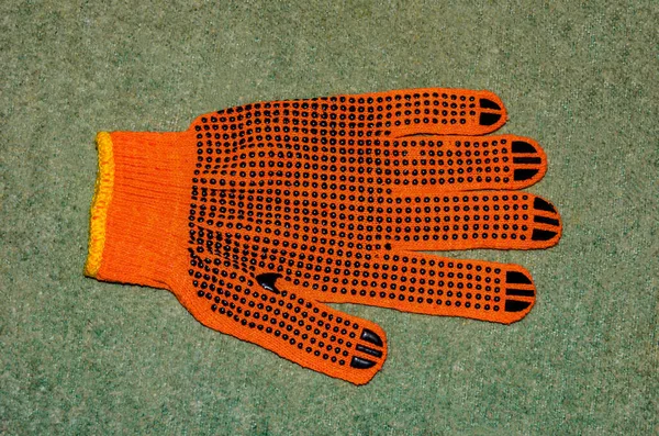 Turuncu iş eldivenleri bahçedeki ahşap bir tahtanın üzerinde yatıyor. .