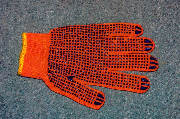 Turuncu iş eldivenleri bahçedeki ahşap bir tahtanın üzerinde yatıyor. .