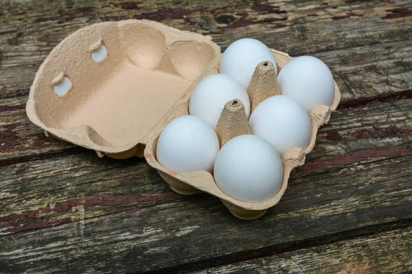 Six chicken eggs in a green egg box, close-up.Top view of chicken eggs in eggs tray on wooden table